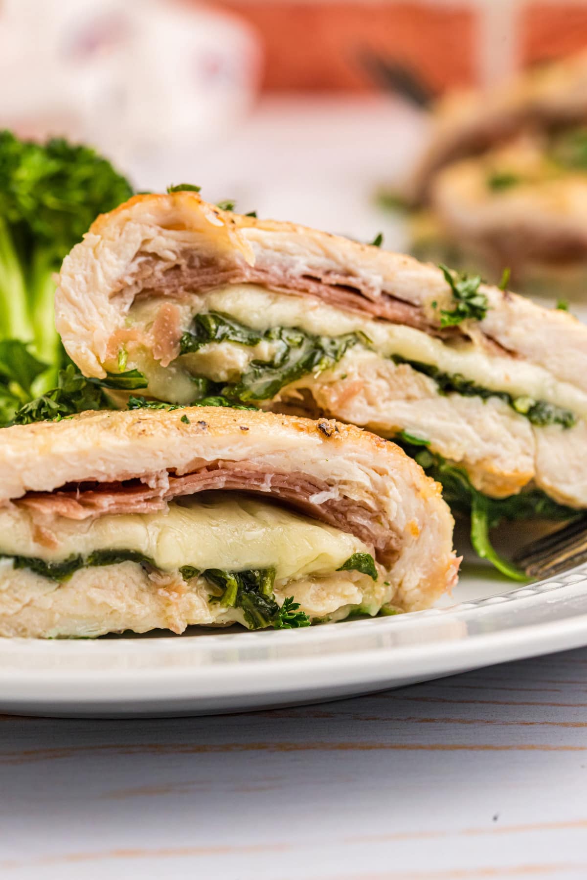 gruyere arugula and prosciutto stuffed chicken breasts cut open on a plate