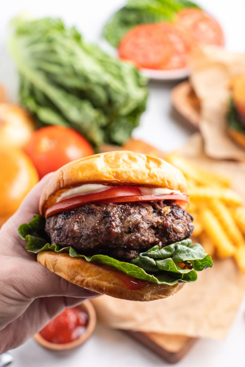 Hamburgers with Cabernet and Sauteed Onions #hamburgers #burgers #cabernet #sauteedonions #recipe #RecipeGirl hand holding hamburger with cabernet and sauteed onions