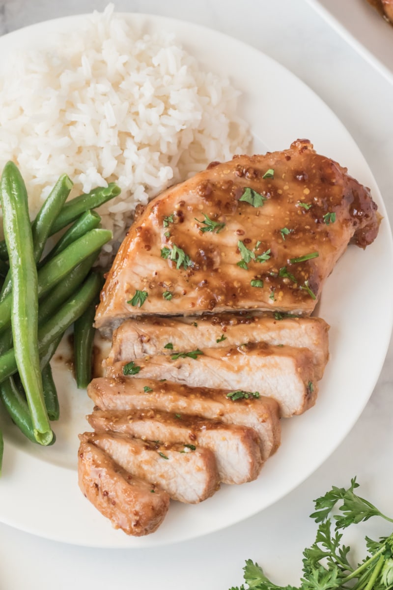 pork chop sliced on plate with green beans and rice