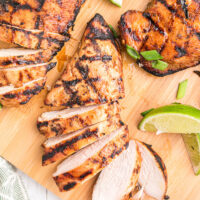 hoisin and lime marinated grilled chicken breasts on a board with lime wedges