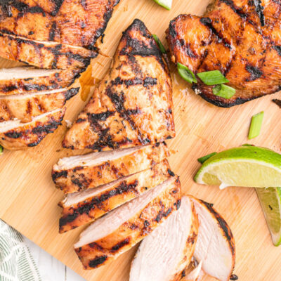 hoisin and lime marinated grilled chicken breasts on a board with lime wedges