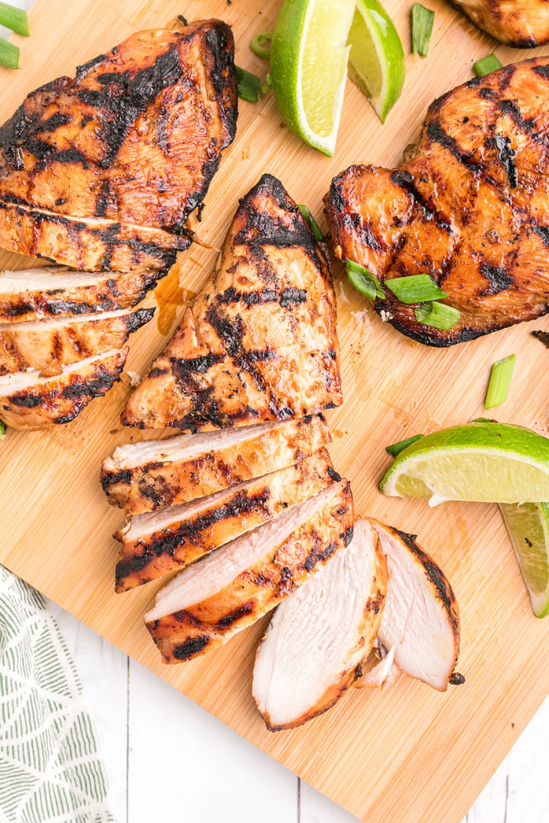 hoisin and lime marinated grilled chicken breasts on a board with lime wedges