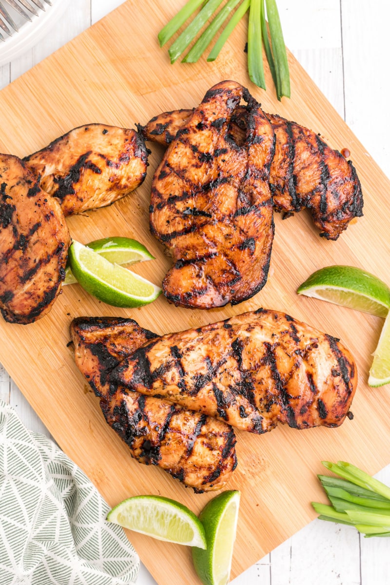 hoisin and lime marinated grilled chicken breasts on a board with lime wedges