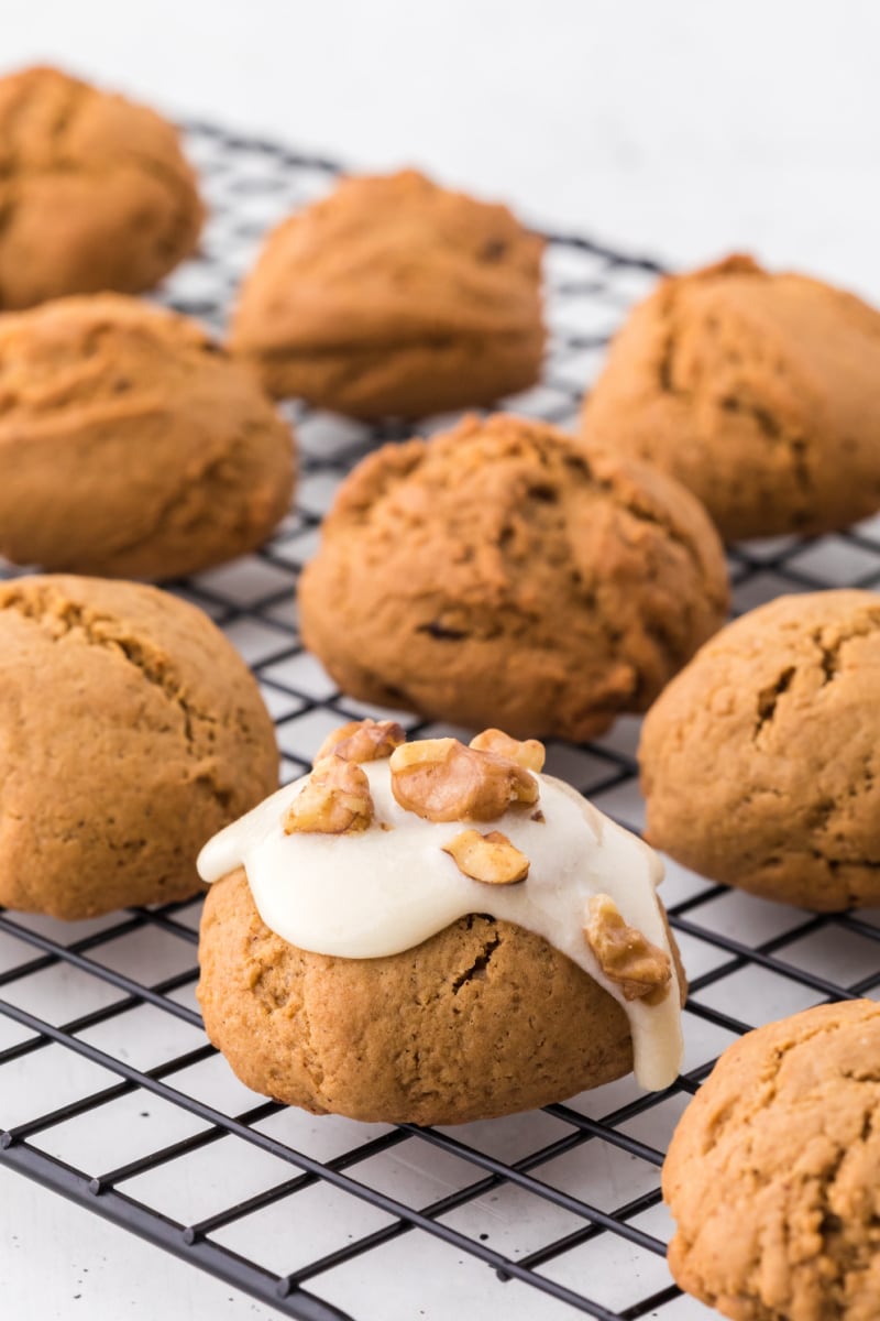 maple walnut spice cookies on a cooling rack with one being iced