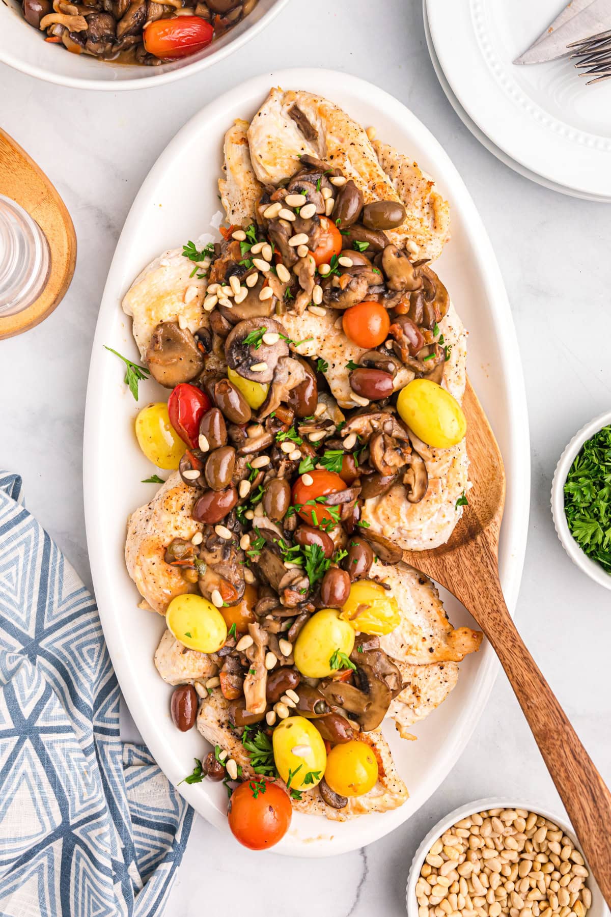 A recipe for sautéed Mediterranean Chicken with big flavors of tomato, garlic, mushrooms, olives, capers and pine nuts. Recipe from RecipeGirl.com. platter of mediterranean chicken