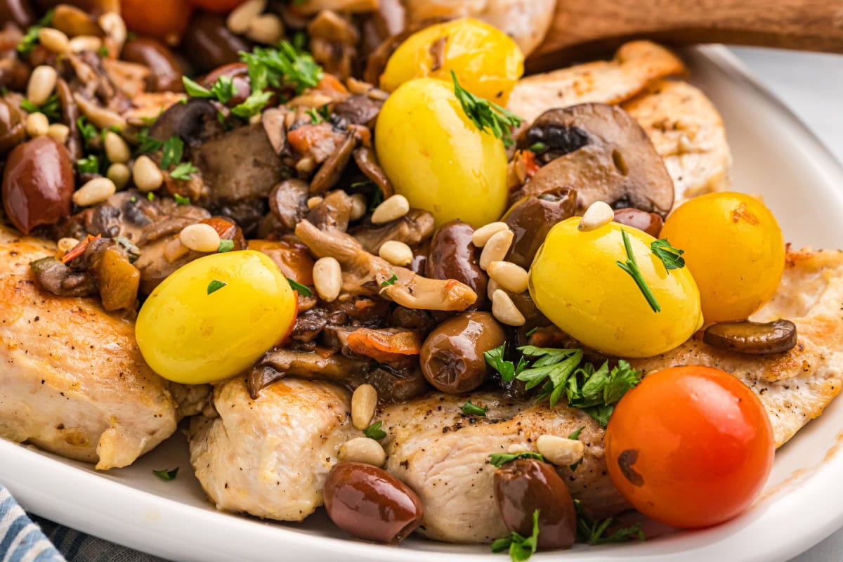 A recipe for sautéed Mediterranean Chicken with big flavors of tomato, garlic, mushrooms, olives, capers and pine nuts. Recipe from RecipeGirl.com. close up of mediterranean chicken