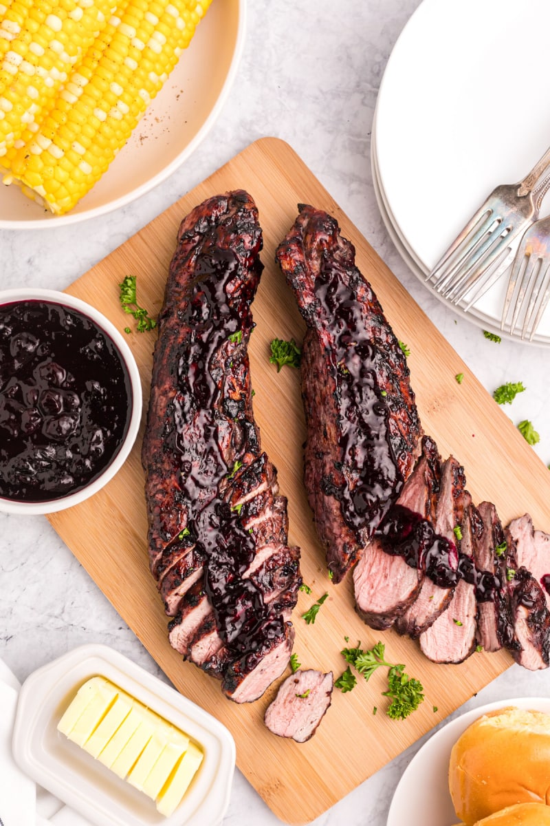 sliced pork tenderloin on a board topped with blueberry bbq sauce