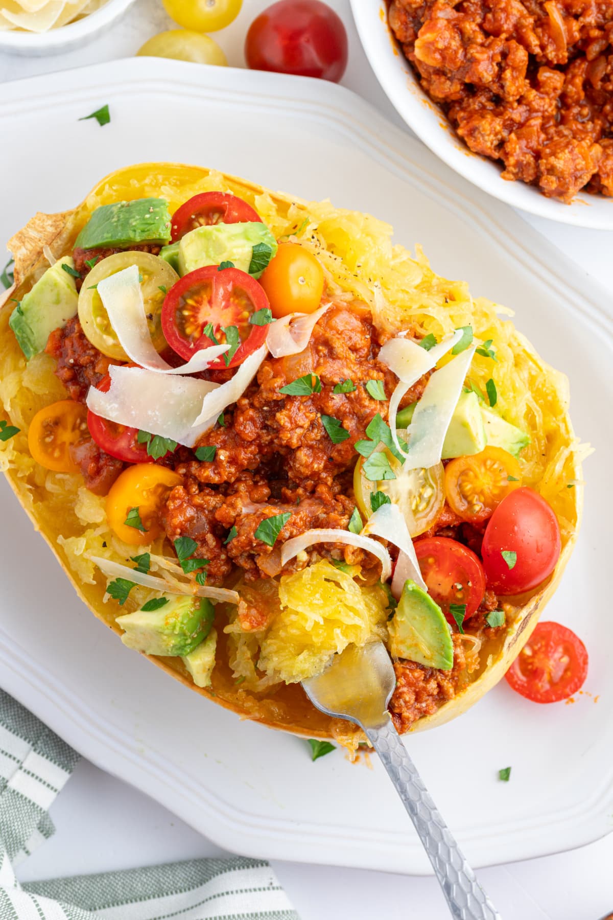 spaghetti squash with spicy meat sauce and garnishes and fork
