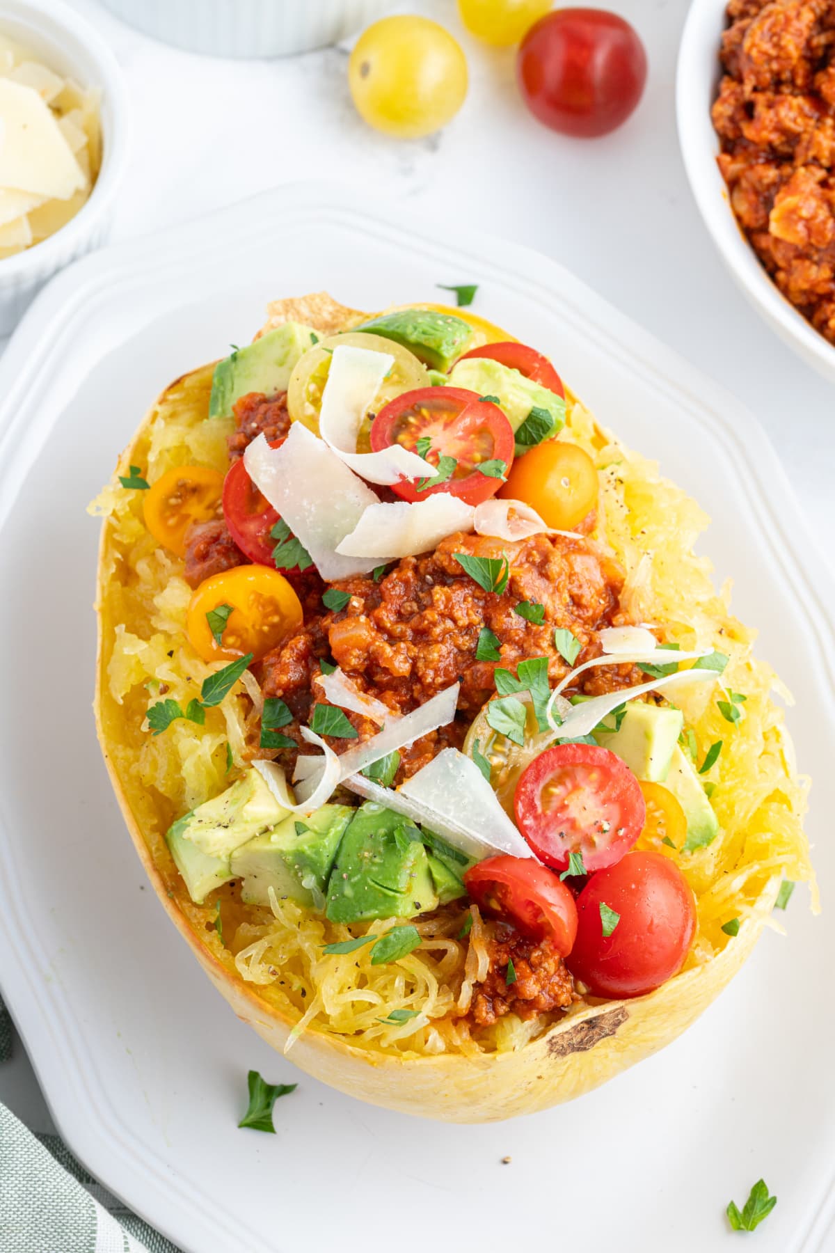 spaghetti squash filled with spicy meat sauce and garnishes