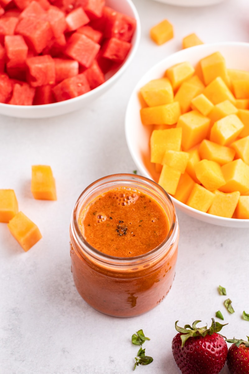 watermelon vinaigrette in a jar with bowls of melon in background