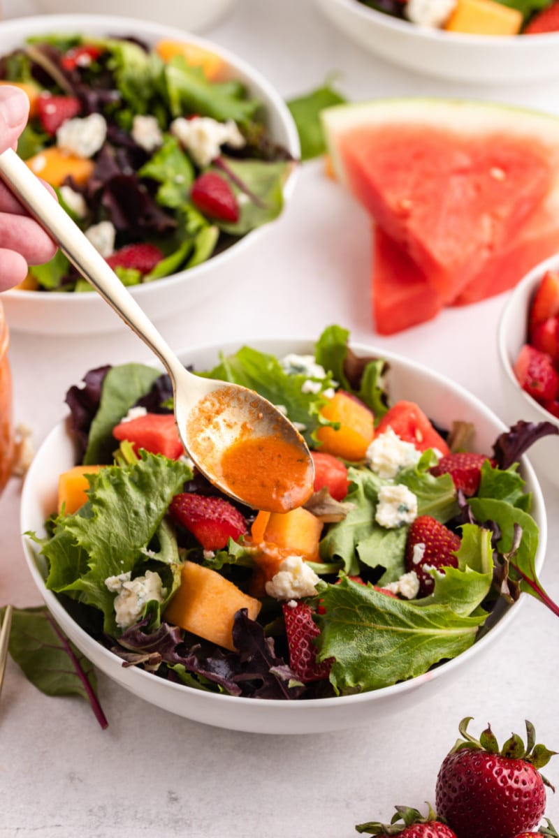 spooning watermelon vinaigrette onto strawberry melon salad