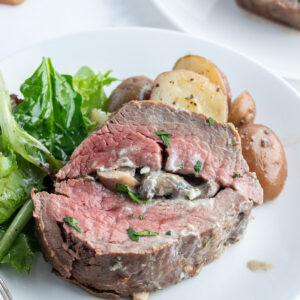 slice of stuffed beef tenderloin on a plate with salad