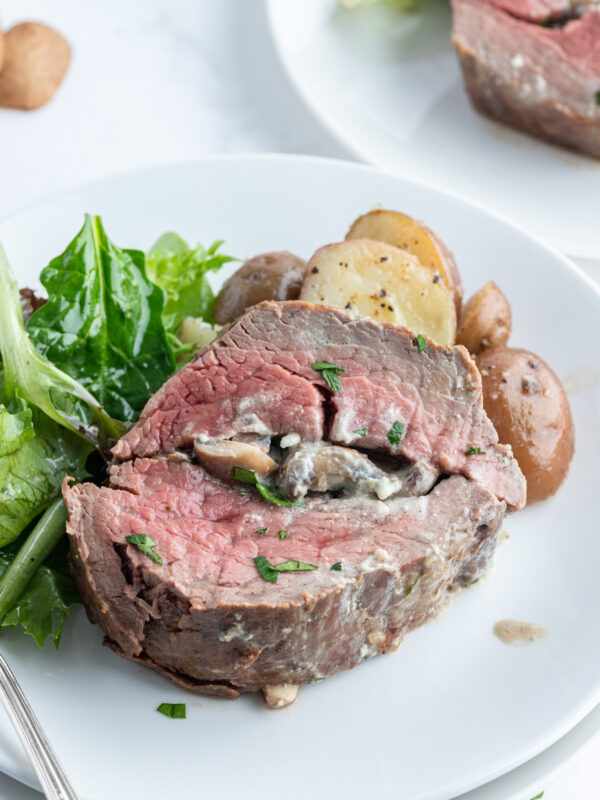slice of stuffed beef tenderloin on a plate with salad