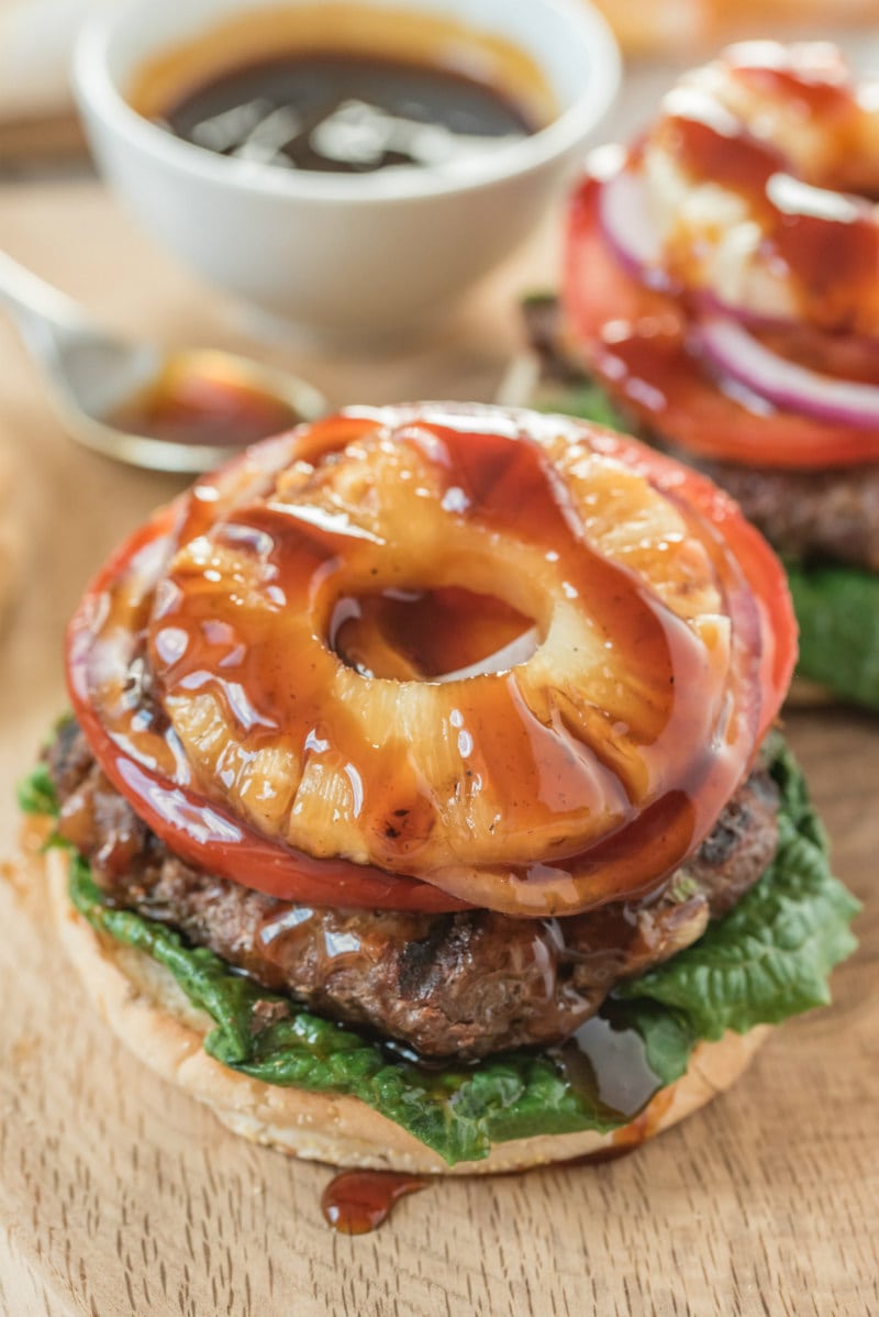 Teriyaki Burgers recipe from RecipeGirl.com #teriyaki #burger #burgers #recipe #RecipeGirl looking down on a teriyaki burger with no bun on top and grilled pineapple with teriyaki glaze dripping over