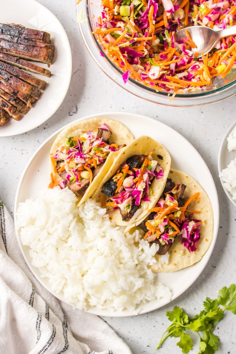 three thai beef tacos on a plate with rice