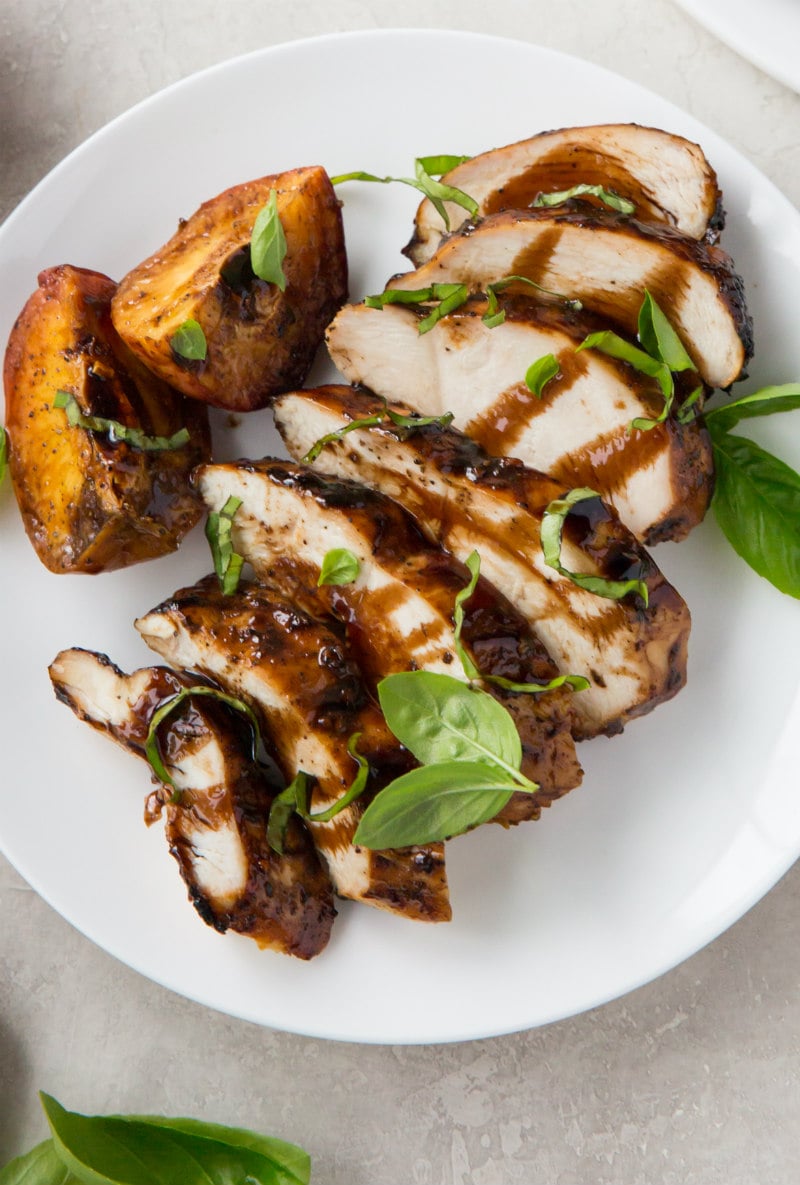 white plate with grilled balsamic sliced chicken and peaches