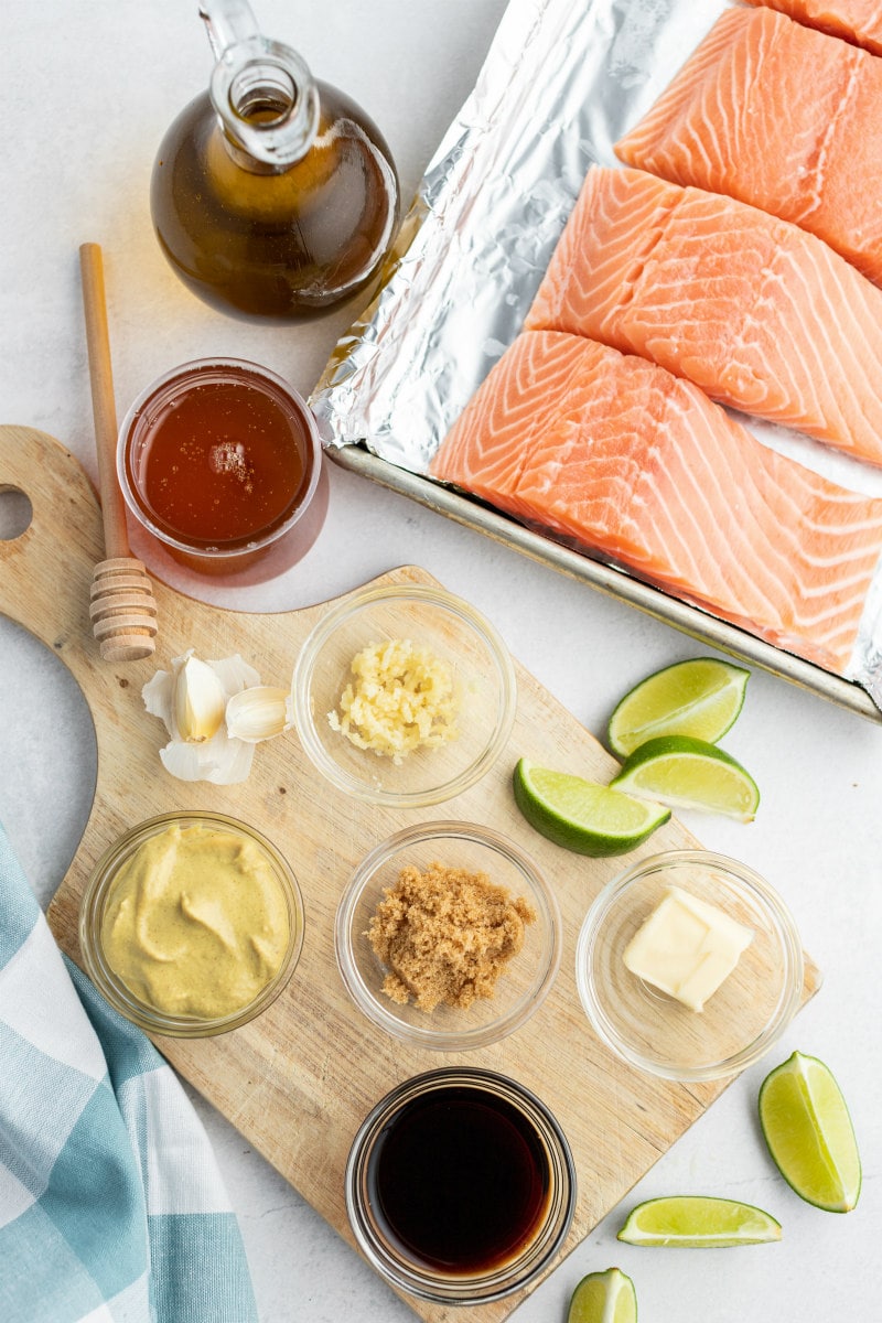 overhead shot of ingredients needed to make barbecued salmon. Ingredients displayed in little glass bowls and cut salmon filets.