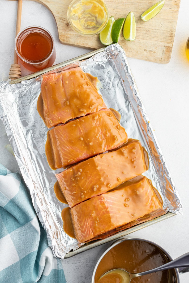 overhead shot of marinated salmon ready for the oven with honey, sauce lime on the side