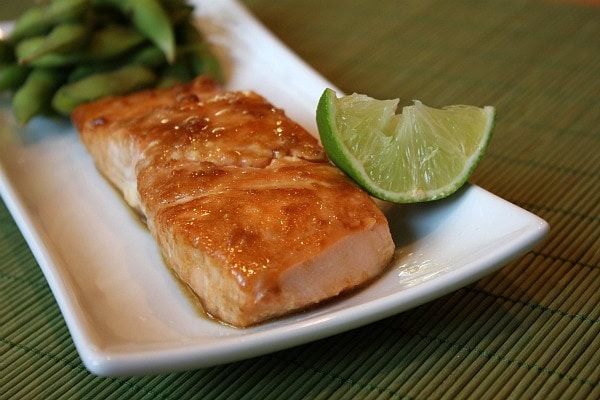 fillet of barbecued salmon on a white serving plate with a lime wedge