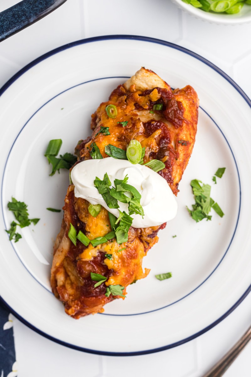 cranberry turkey enchilada on a plate with sour cream on top