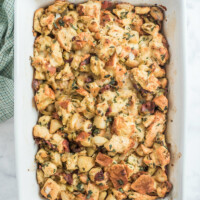 dressing with apples, bacon and caramelized onions in white casserole dish