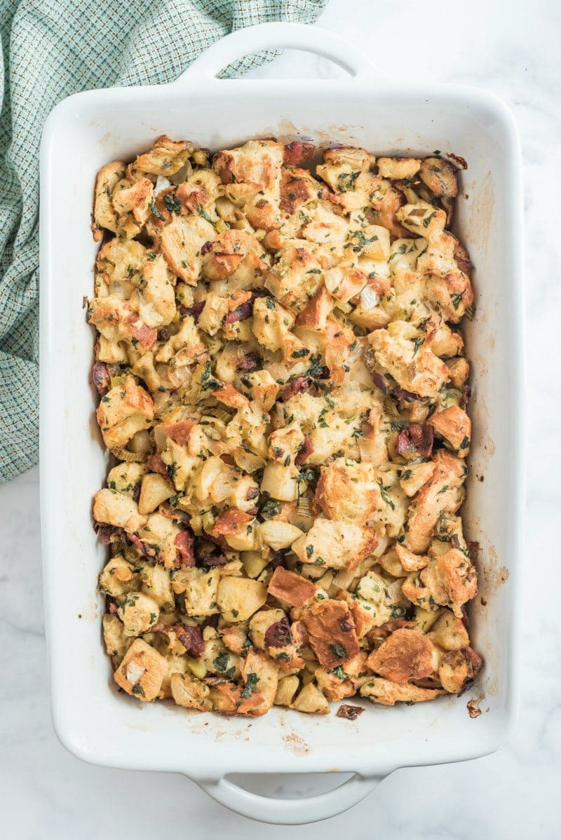 dressing with apples, bacon and caramelized onions in white casserole dish