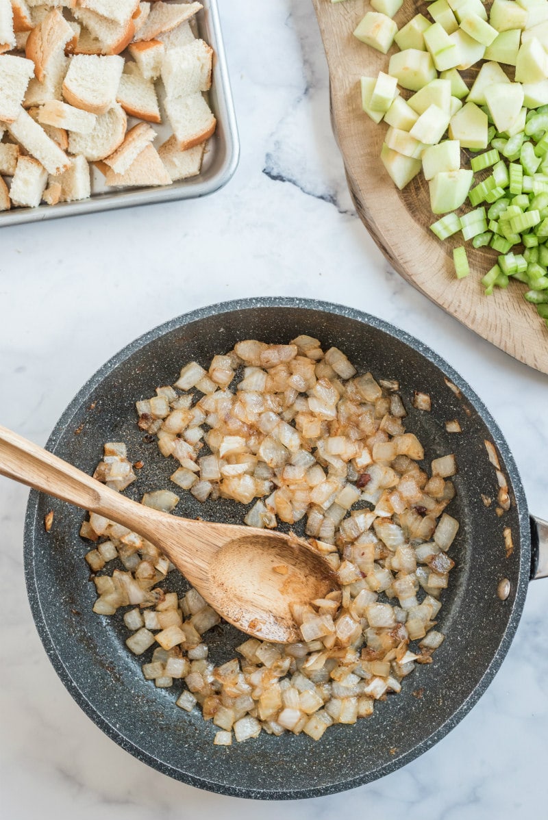 sauteeing onions in a skillet with wooden spoon