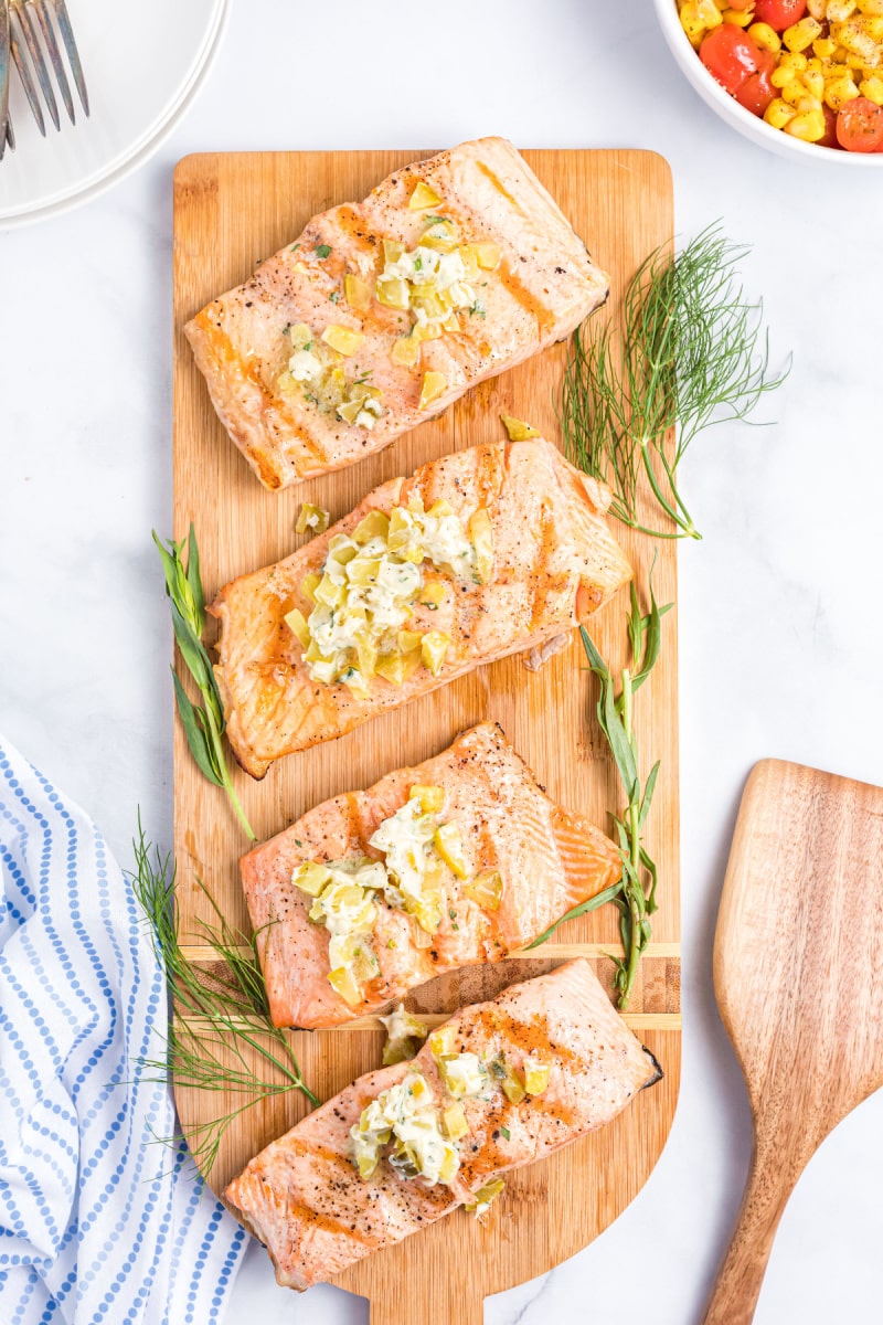 grilled salmon fillets with dill pickle butter on a board