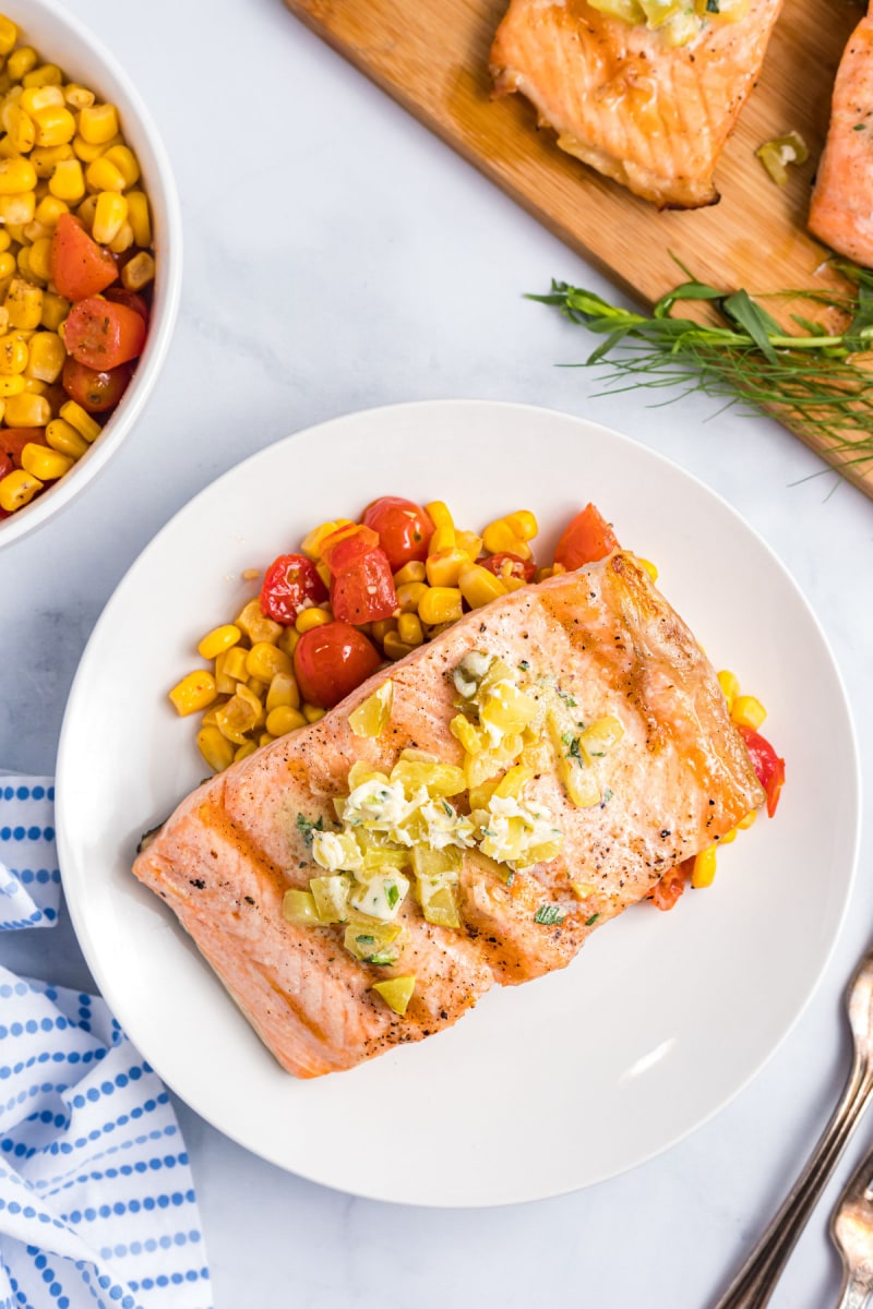 grilled salmon on a plate with corn and tomato