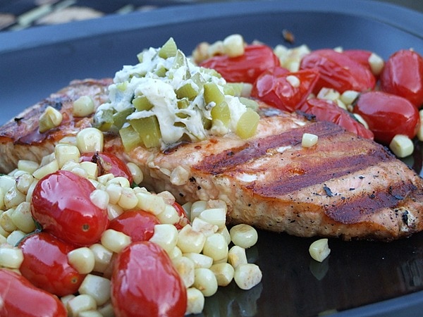 grilled salmon topped with dill pickle butter and served with corn and tomato