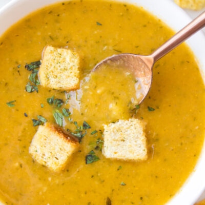 bowl of zucchini fresh oregano soup topped with croutons and spoon