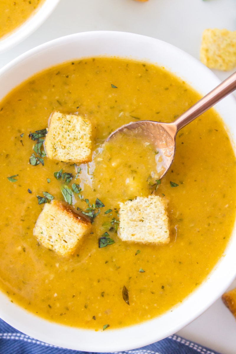 bowl of zucchini fresh oregano soup topped with croutons and spoon