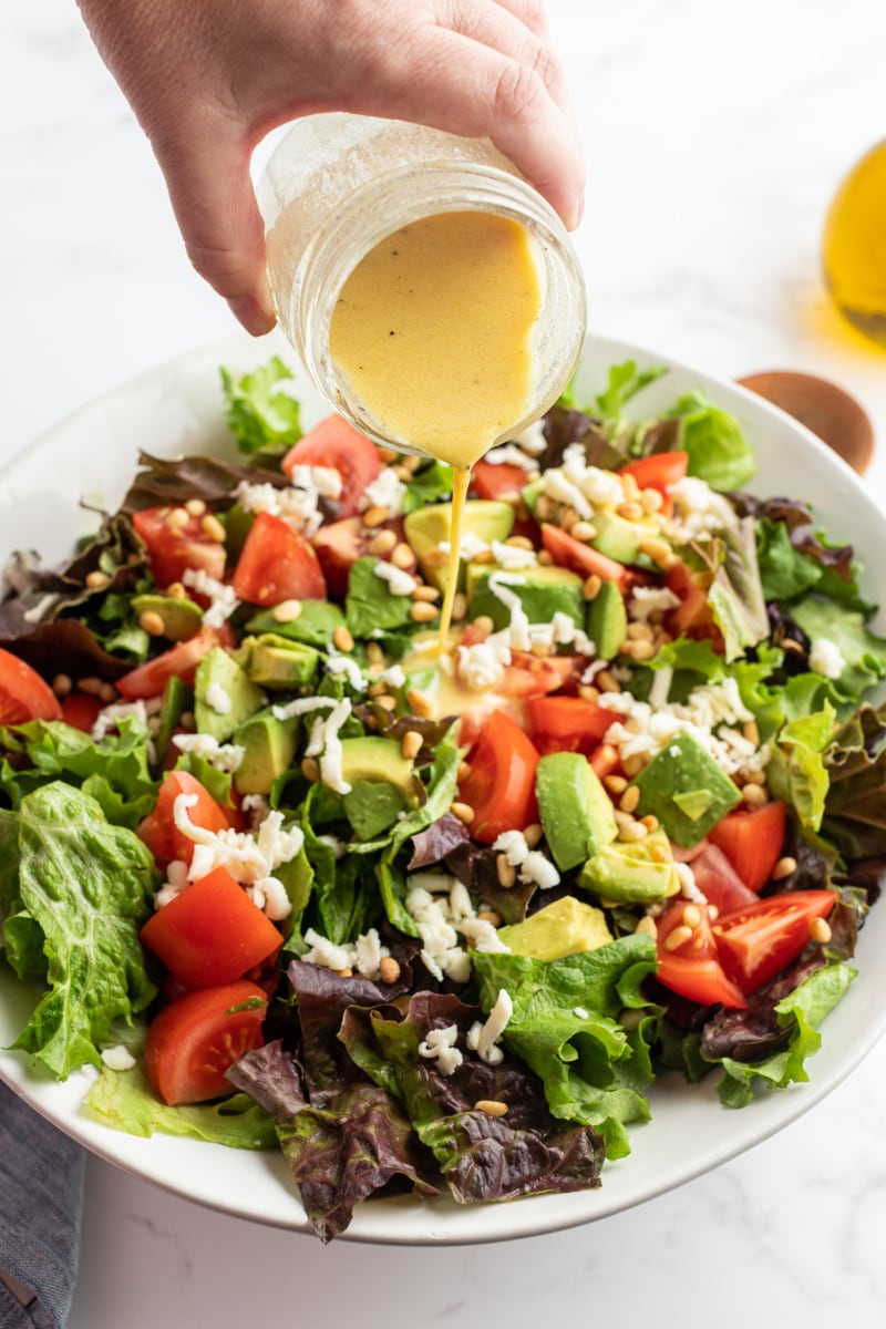 dressing being poured on salad