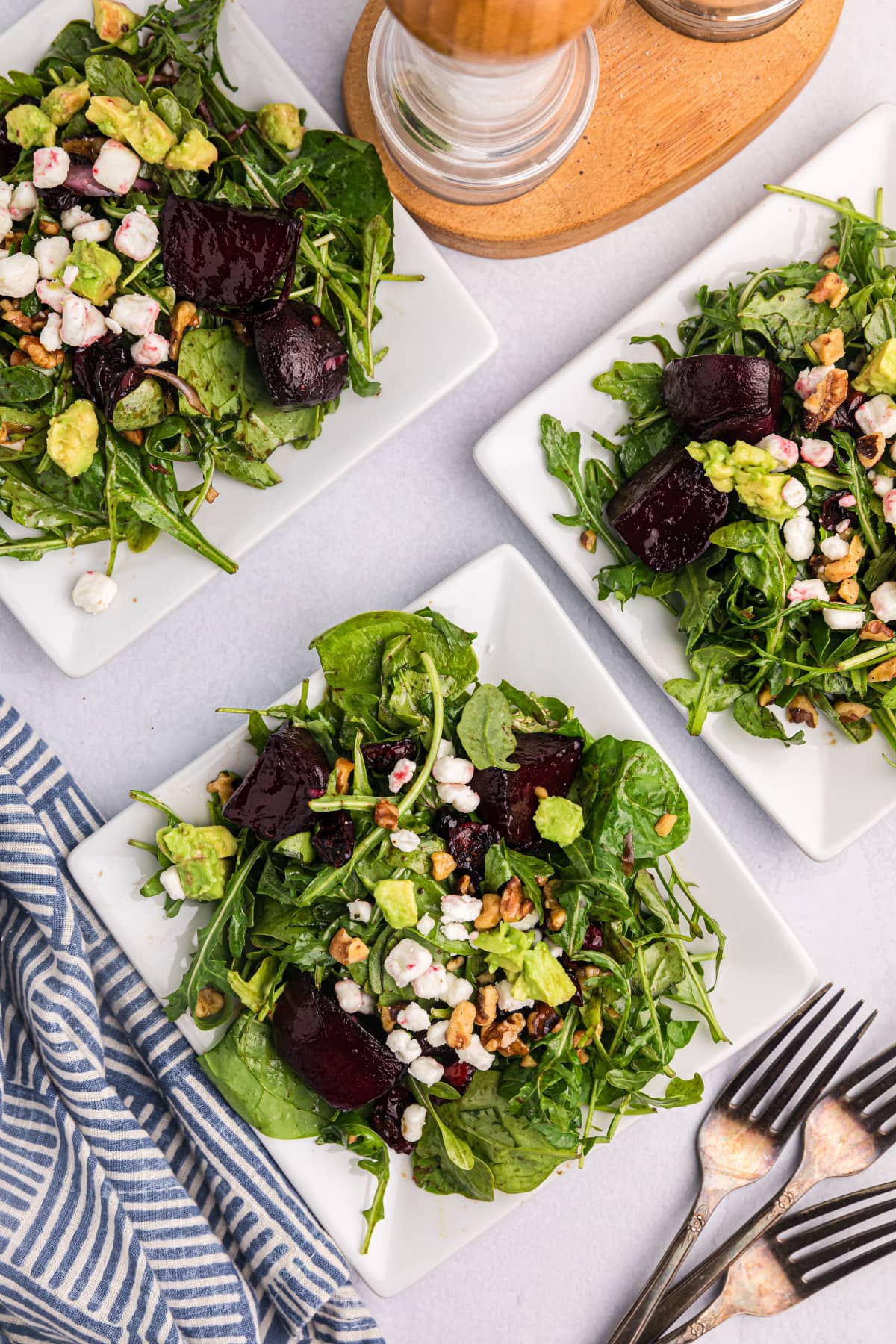 overhead shot of three plates of beet and goat cheese arugula salad