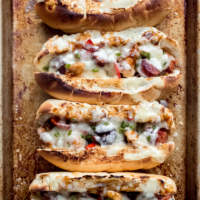four chicken and sausage hoagies on a baking sheet