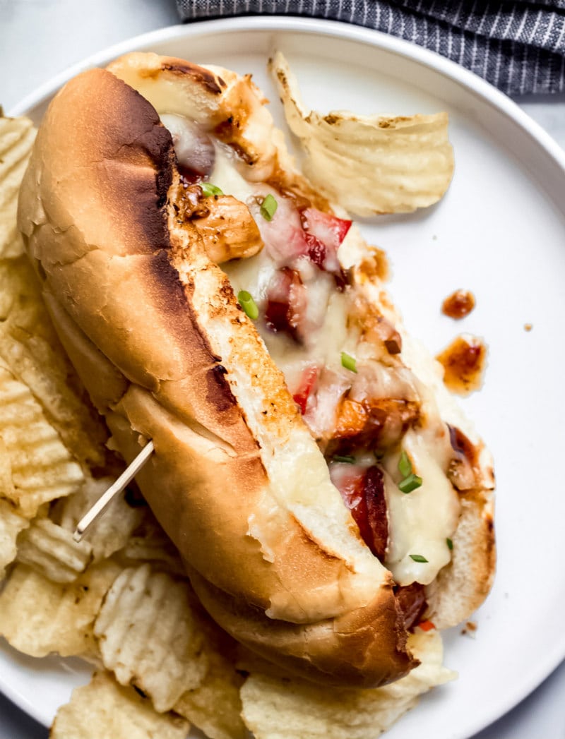 chicken and sausage hoagie on a white plate served with potato chips