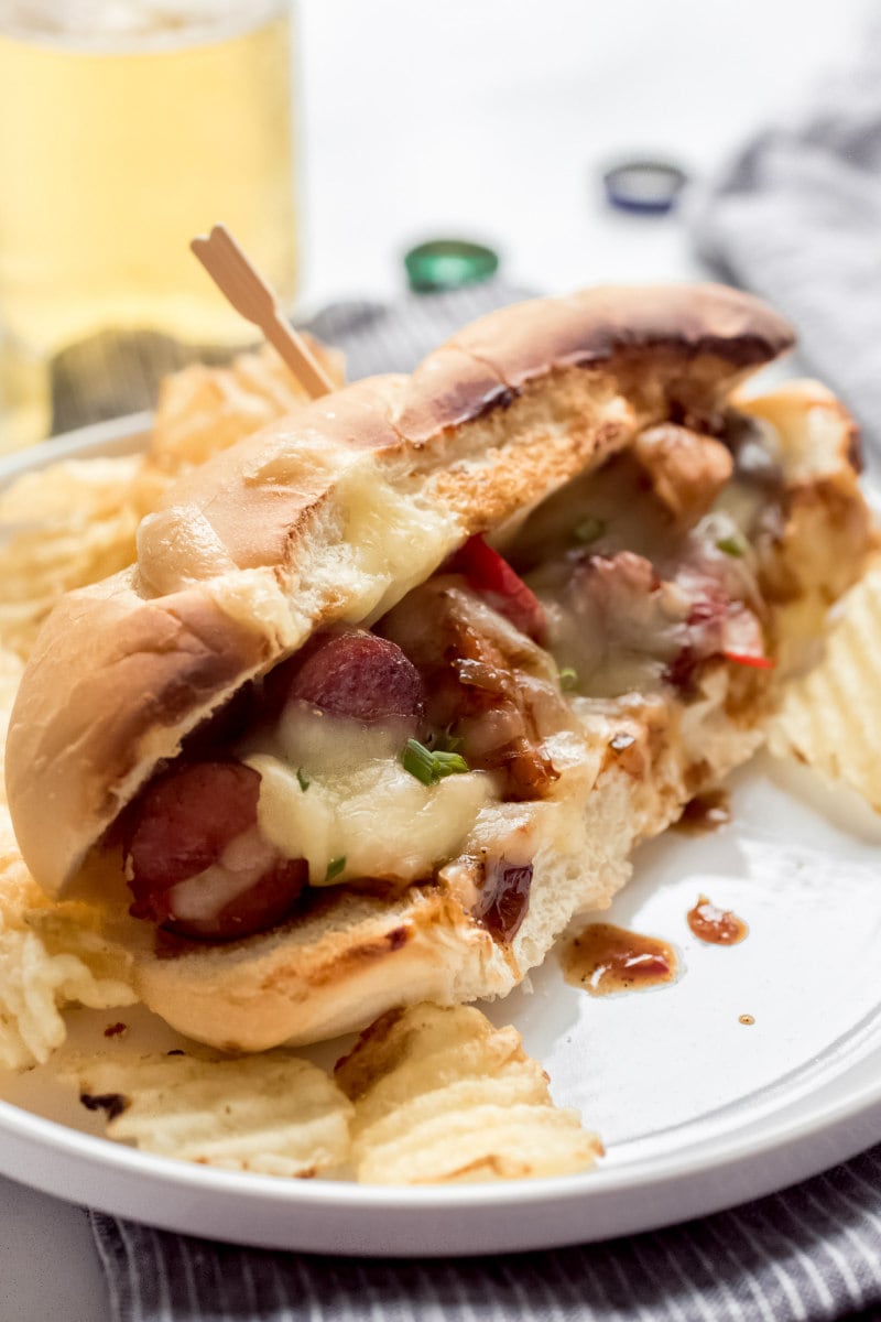 Chicken and Sausage Hoagie with a toothpick through the middle served on a plate with potato chips