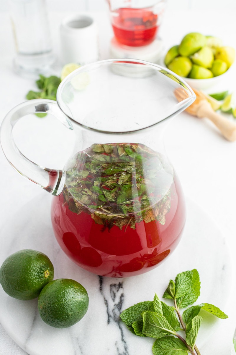 making cranberry mojitos in a glass pitcher