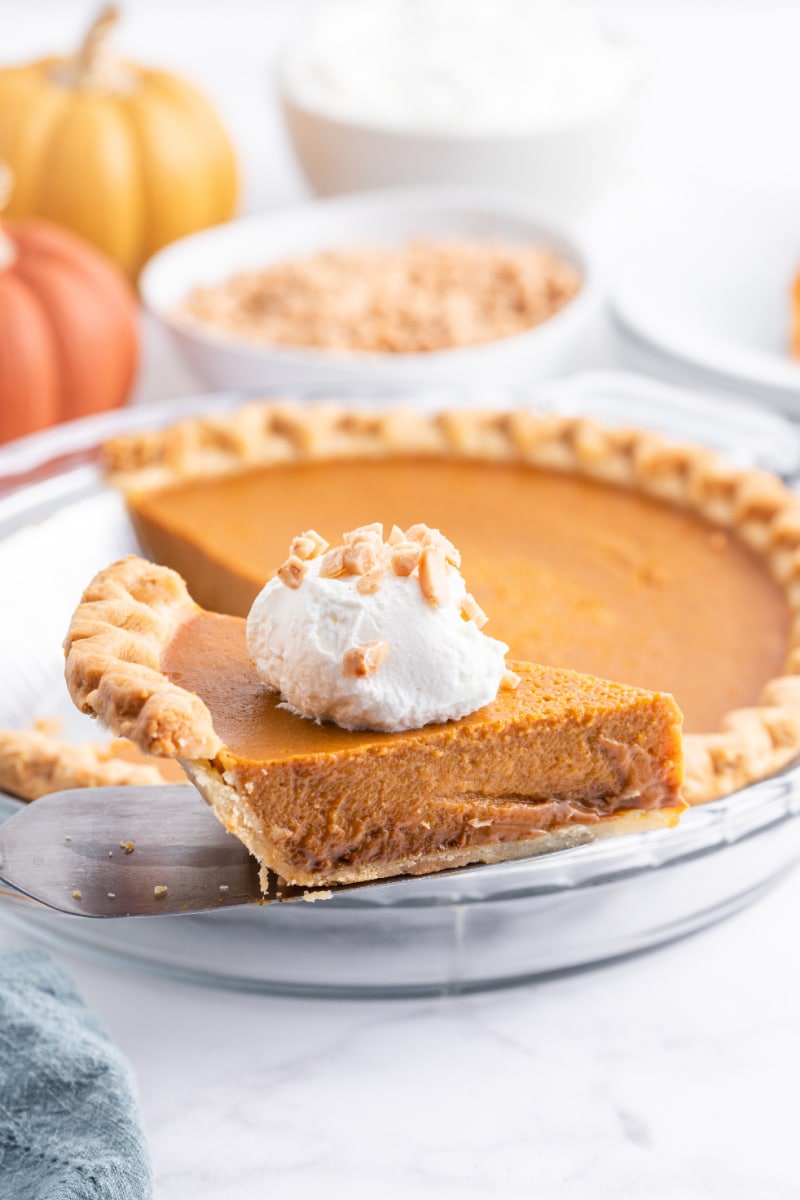 spatula taking out slice of pumpkin pie from whole pie