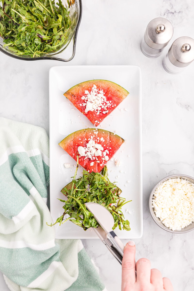 showing prep of assembling grilled watermelon salad on platter