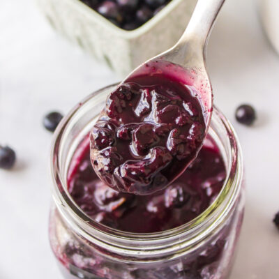 spooning hot blueberry sauce out of a jar