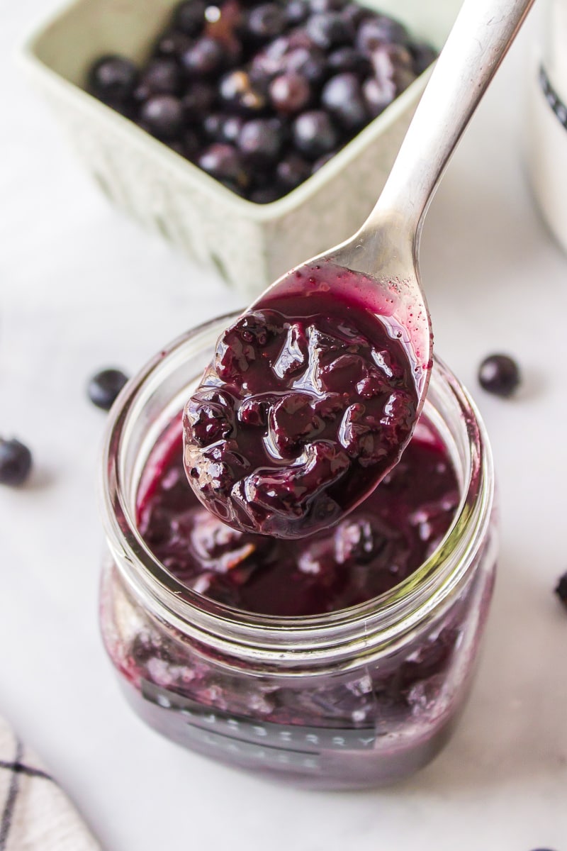 spooning hot blueberry sauce out of a jar