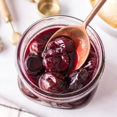 spooning out hot cherry sauce out of jar