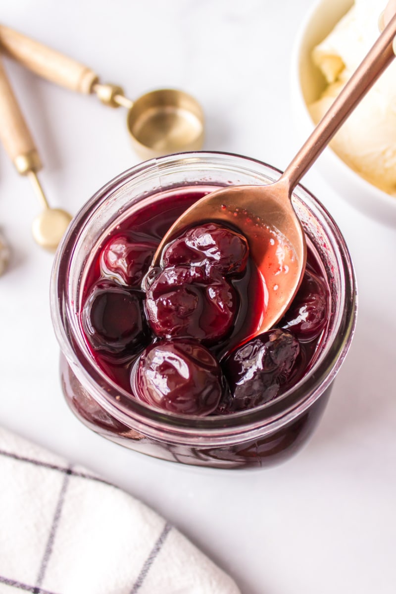 spooning out hot cherry sauce out of jar