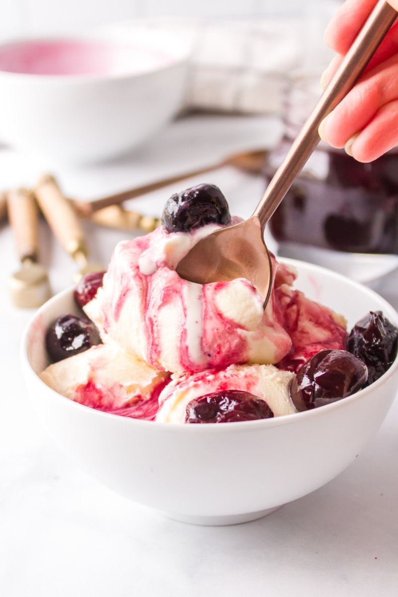 ice cream in bowl with hot cherry sauce and spoon