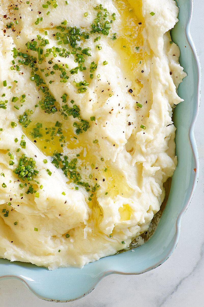 Casserole dish of Make Ahead Mashed Potatoes with melted butter
