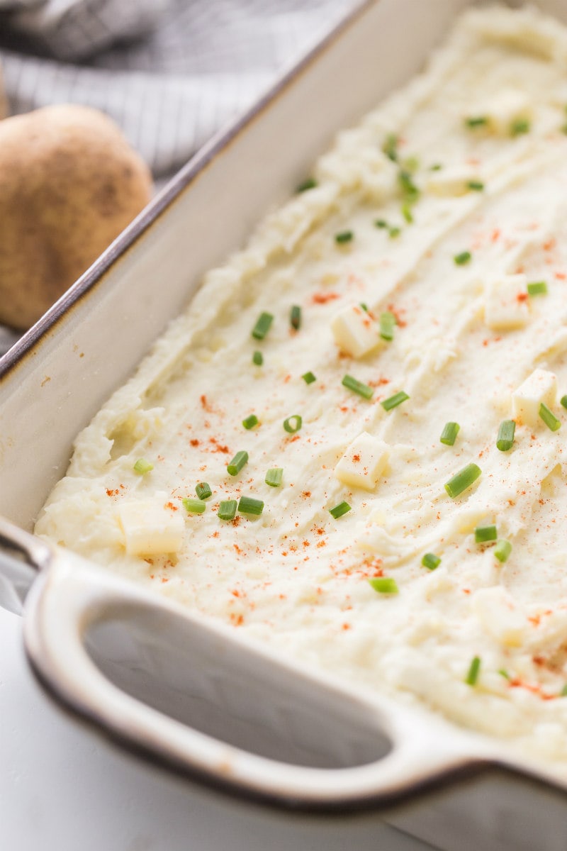Creamy Oven Baked Mashed Potatoes in a casserole dish ready for the oven