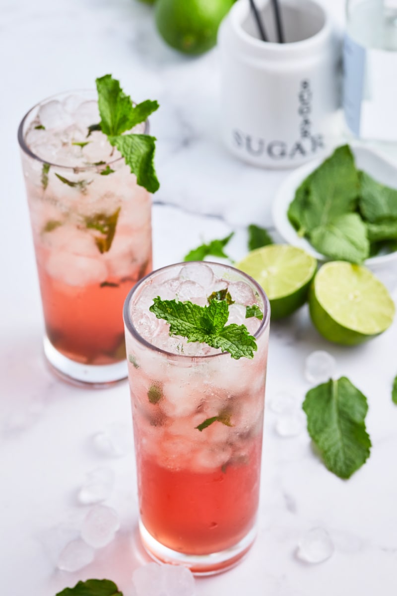 pomegranate mojitos in tall glasses with lime and mint