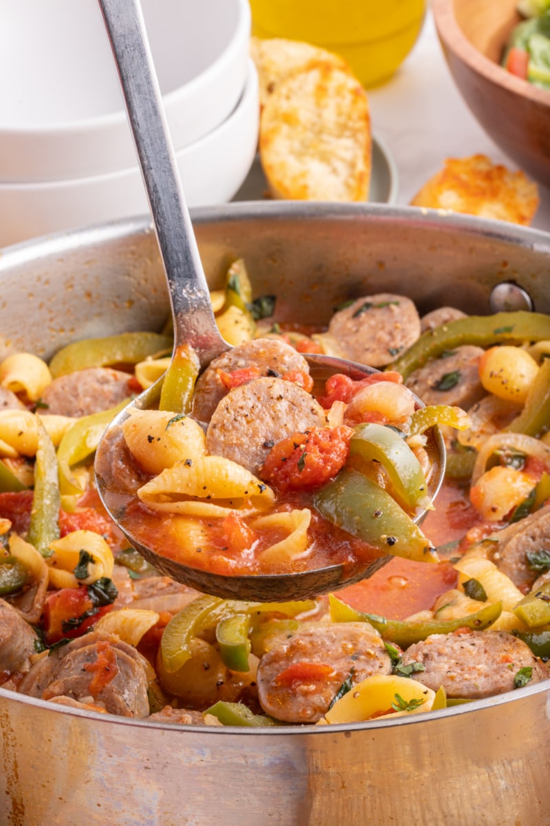 ladle full of sausage and pepper stew above pot