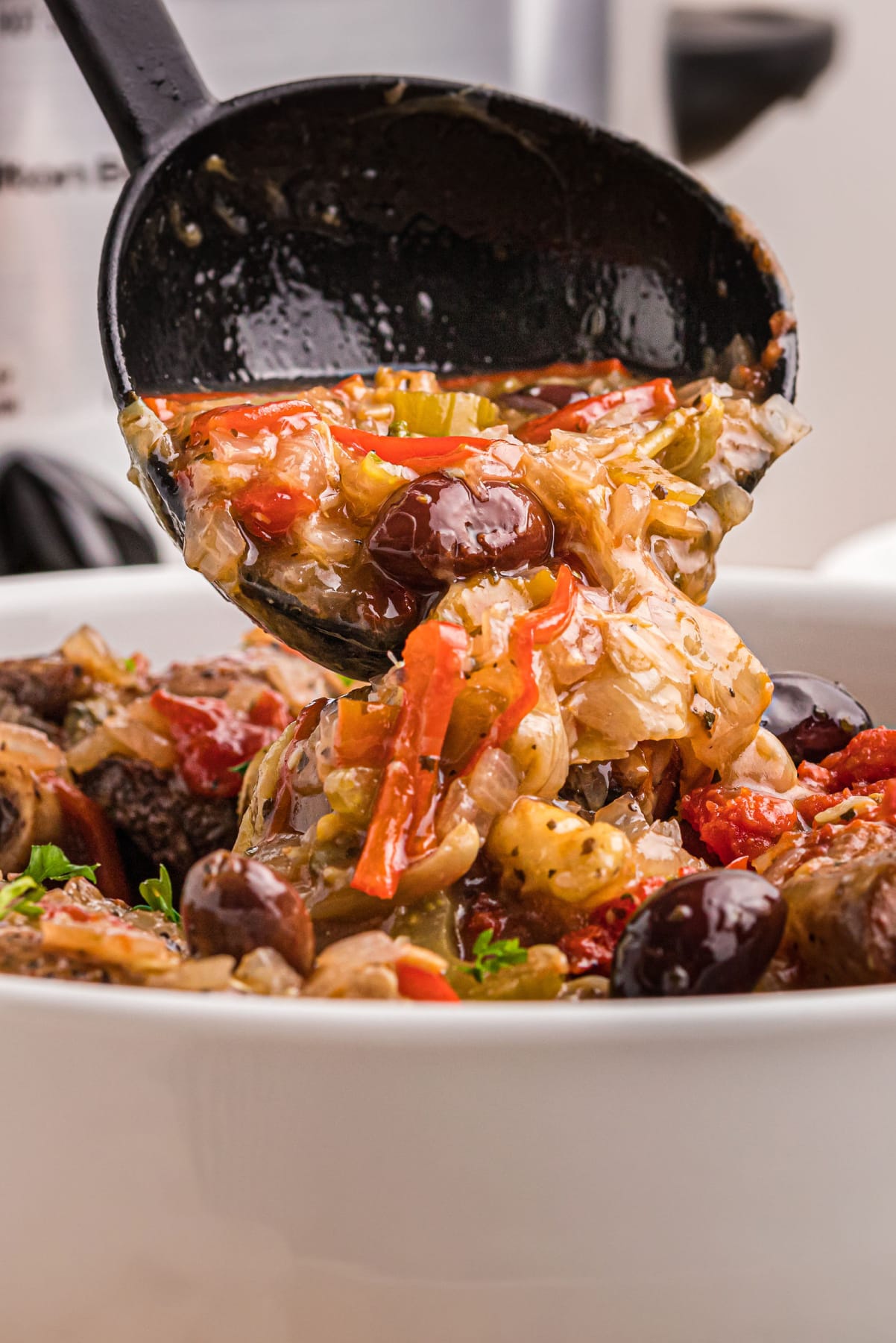 pouring artichoke caponata onto lamb shanks in dish